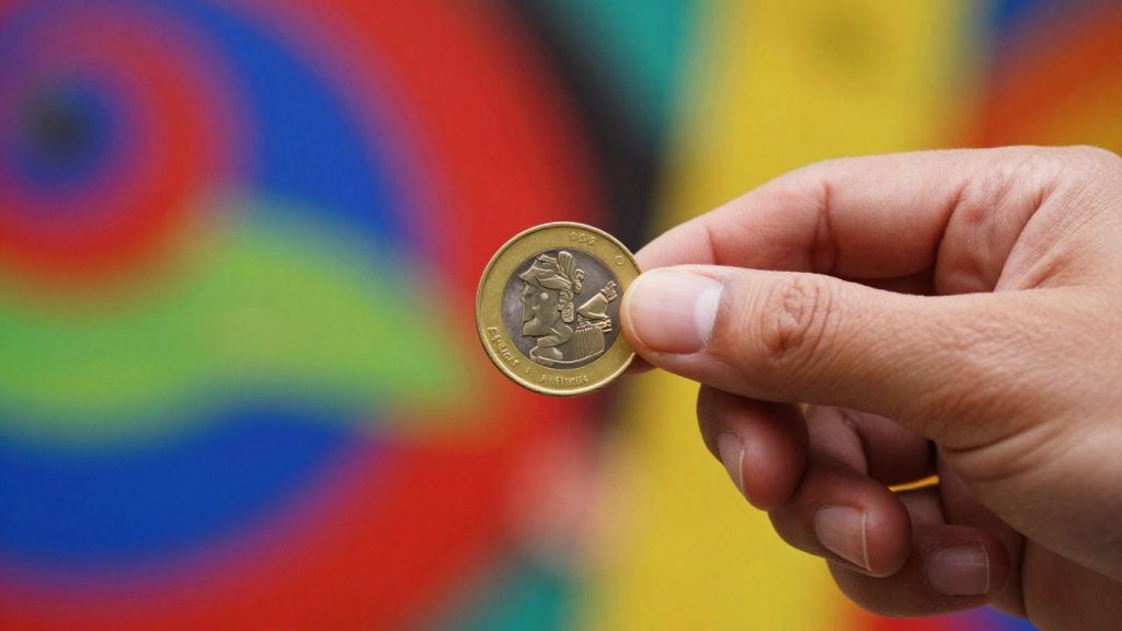 Golden coin held in hand, abstract market background.